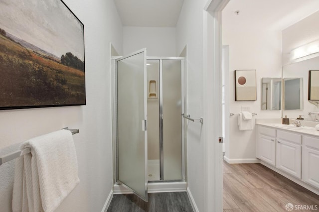 bathroom featuring wood-type flooring, a shower with door, and vanity