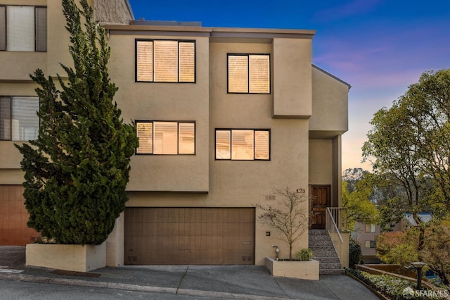 view of front of property featuring driveway, an attached garage, and stucco siding