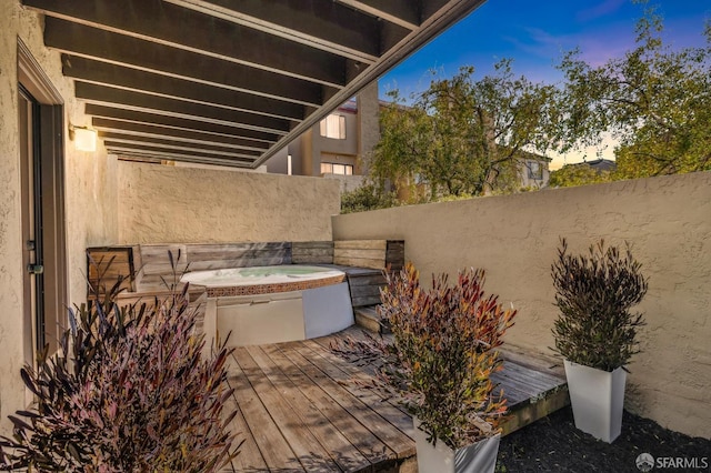 patio terrace at dusk featuring a jacuzzi and fence