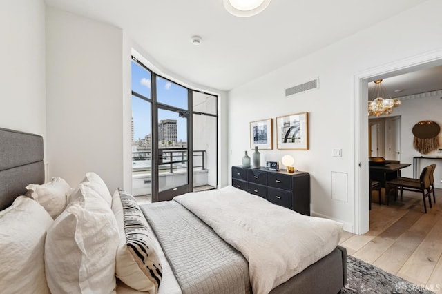 bedroom with expansive windows, access to outside, and light hardwood / wood-style floors