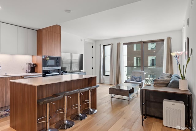 kitchen with light wood-type flooring, white cabinetry, appliances with stainless steel finishes, and a center island