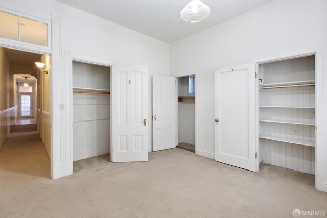unfurnished bedroom featuring two closets and carpet flooring