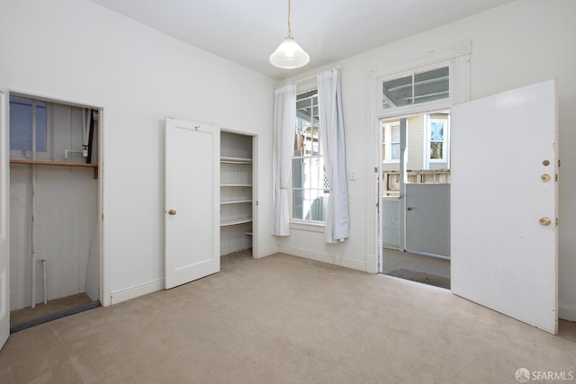 unfurnished bedroom with baseboards, carpet, and two closets