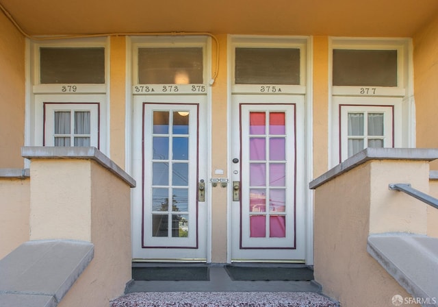 doorway to property featuring covered porch and stucco siding