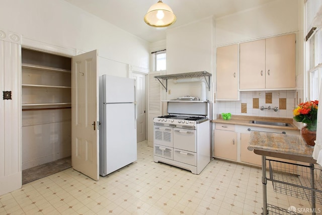kitchen featuring tasteful backsplash, a sink, light countertops, light floors, and white appliances