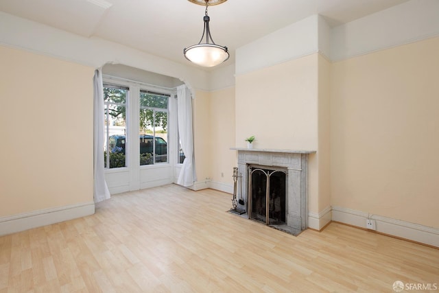 unfurnished living room with light wood-style floors, a fireplace with flush hearth, and baseboards