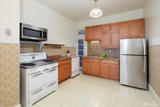 kitchen featuring a sink, light floors, stainless steel appliances, and brown cabinets