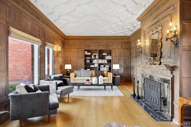 living room featuring an ornate ceiling, light wood-style floors, ornamental molding, and wood walls