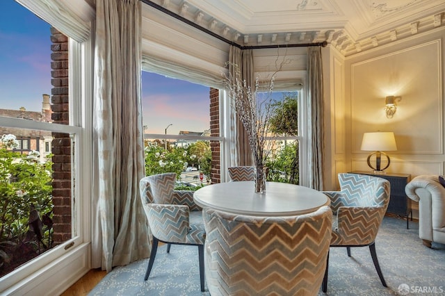 dining room featuring a decorative wall, a healthy amount of sunlight, and ornamental molding