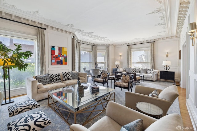 living room with a wainscoted wall, wood finished floors, ornamental molding, and a decorative wall