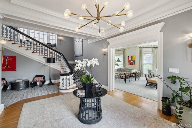 entryway with stairway, an inviting chandelier, wood finished floors, and ornamental molding