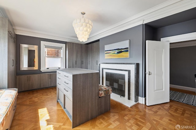 kitchen featuring a fireplace with raised hearth, crown molding, a chandelier, decorative light fixtures, and light countertops