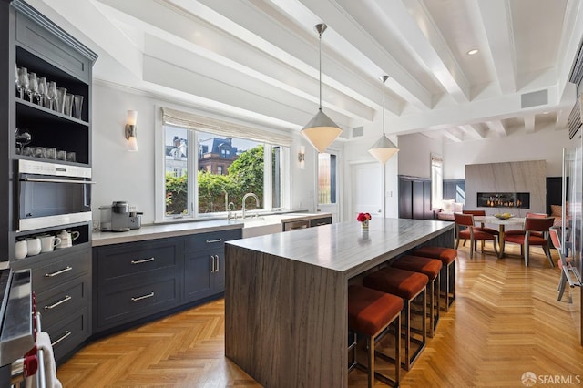 kitchen with beam ceiling, a breakfast bar, open floor plan, a center island, and stainless steel oven