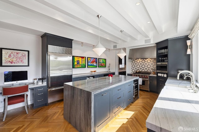 kitchen with a kitchen island, premium appliances, a sink, wall chimney exhaust hood, and tasteful backsplash