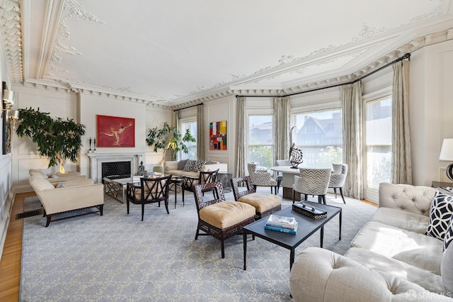 living area featuring crown molding, wood finished floors, and a fireplace