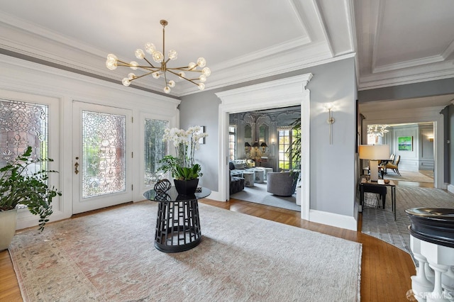 entryway with a chandelier, crown molding, baseboards, and wood finished floors