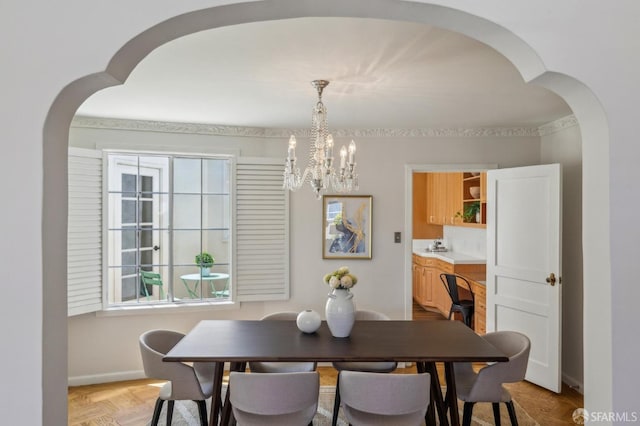 dining area with arched walkways, a chandelier, baseboards, and healthy amount of natural light