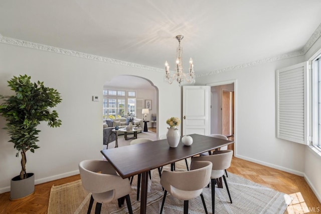dining area featuring arched walkways, a chandelier, and baseboards