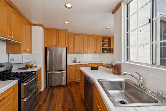 kitchen with appliances with stainless steel finishes, tile countertops, a sink, tasteful backsplash, and recessed lighting