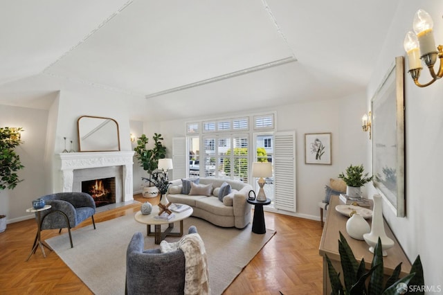living room with a lit fireplace and baseboards