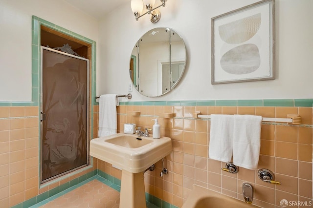bathroom featuring tile walls, a stall shower, and wainscoting