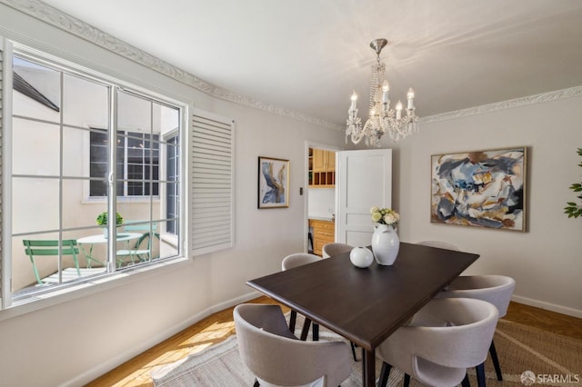 dining space featuring baseboards, a chandelier, and wood finished floors