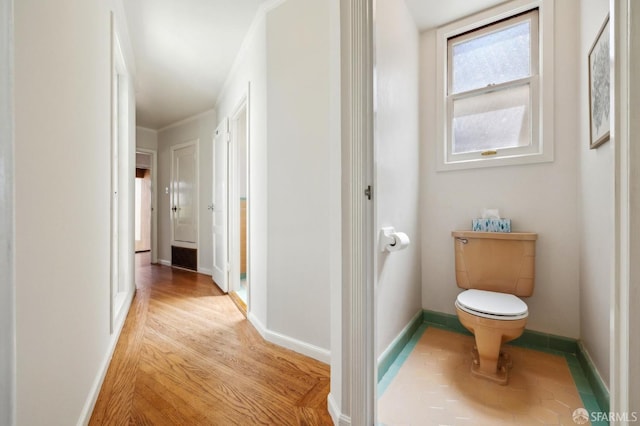 corridor featuring light wood-type flooring and baseboards