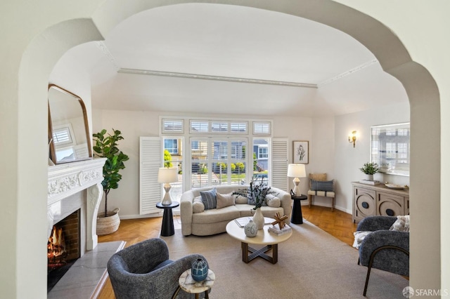 living room with a high end fireplace, arched walkways, plenty of natural light, and baseboards