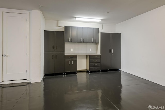 kitchen featuring finished concrete flooring, light countertops, and backsplash