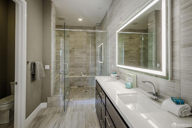 bathroom with toilet, a sink, visible vents, a shower stall, and double vanity