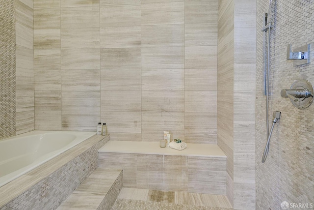 full bathroom featuring a tile shower and a bath