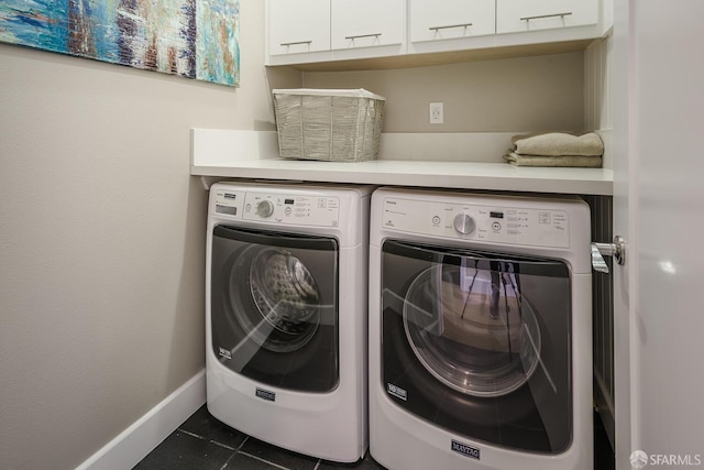 laundry room with washer and dryer, cabinet space, dark tile patterned floors, and baseboards