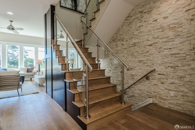 stairway with ceiling fan, baseboard heating, and hardwood / wood-style flooring