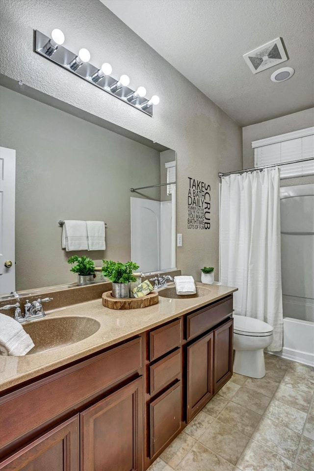 full bathroom featuring shower / bath combination with curtain, vanity, toilet, and a textured ceiling