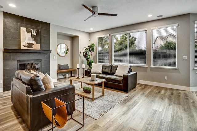 living room featuring a fireplace, light hardwood / wood-style floors, and ceiling fan