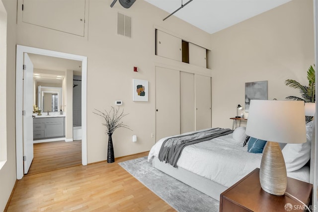 bedroom featuring ensuite bath, a closet, sink, and light hardwood / wood-style flooring