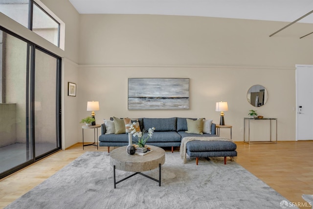 living room with a towering ceiling and light wood-type flooring