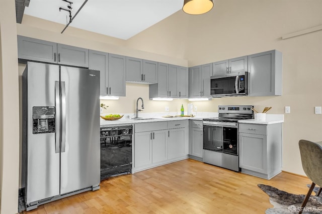 kitchen featuring gray cabinets, sink, stainless steel appliances, and light hardwood / wood-style flooring