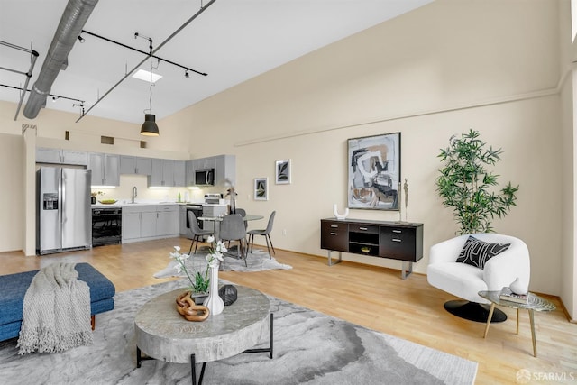 living room featuring sink, high vaulted ceiling, beverage cooler, and light wood-type flooring