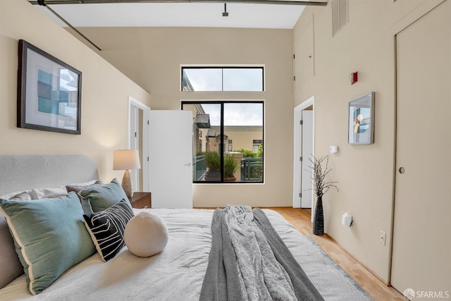 bedroom with light wood-type flooring and a high ceiling