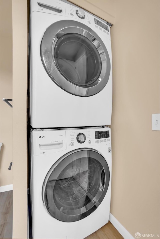 washroom with wood-type flooring and stacked washing maching and dryer