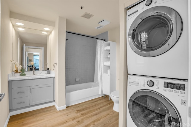 laundry area featuring stacked washer / drying machine, light wood-type flooring, and sink