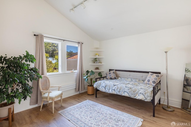 bedroom featuring track lighting, baseboards, wood finished floors, and high vaulted ceiling