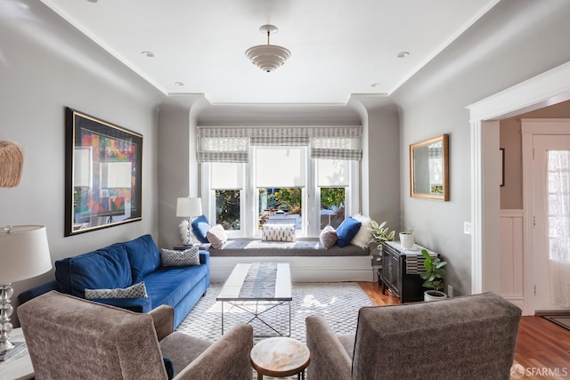 living area with crown molding and light wood-style floors