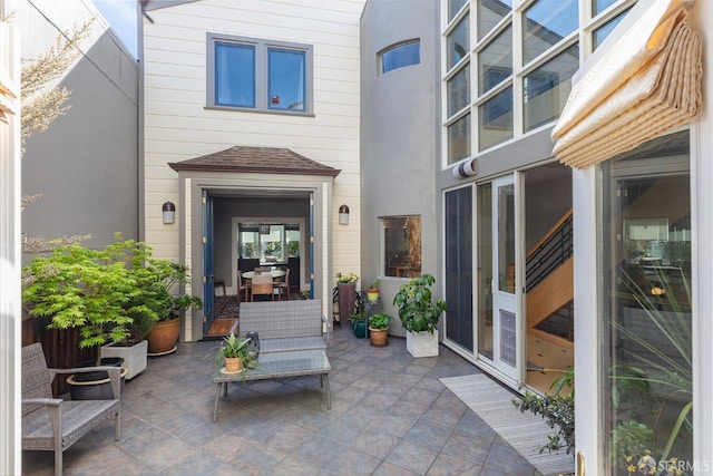 view of exterior entry featuring a patio and roof with shingles