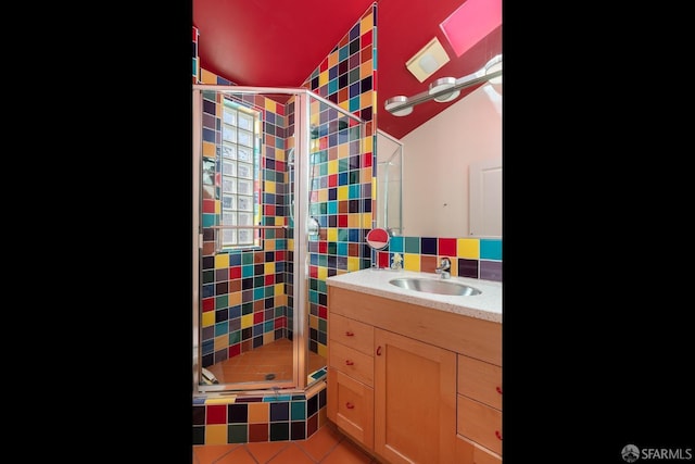 full bathroom with vanity, lofted ceiling, tile patterned flooring, and a stall shower