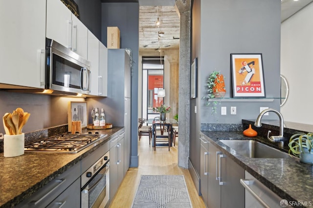 1 S Park St Unit 308, San Francisco, CA 94107 - kitchen featuring stainless steel appliances, light wood-style floors, a sink, dark stone countertops, and white cabinets