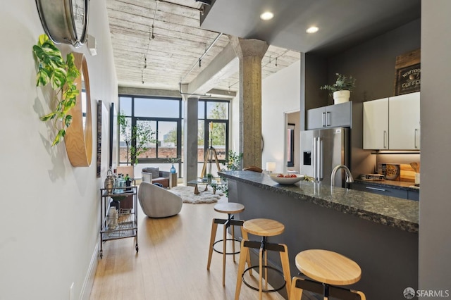 1 S Park St Unit 308, San Francisco, CA 94107 - kitchen featuring stainless steel fridge, a kitchen bar, light wood-style flooring, dark stone counters, and baseboards