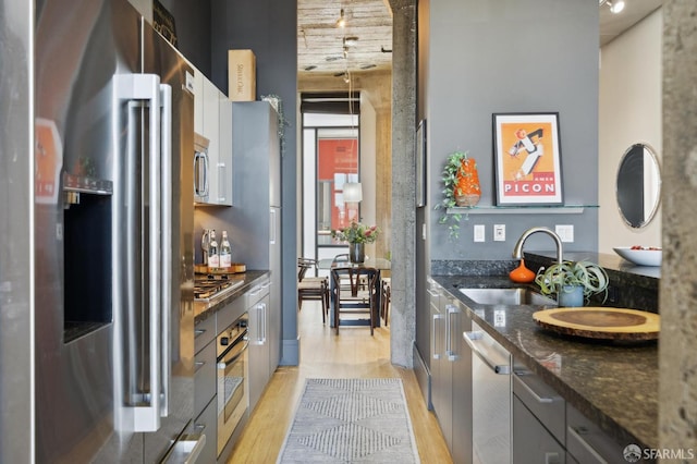 1 S Park St Unit 308, San Francisco, CA 94107 - kitchen featuring stainless steel appliances, a sink, light wood finished floors, and dark stone counters