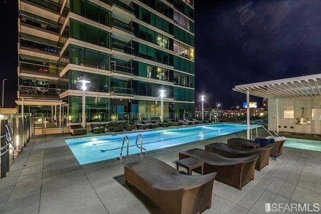 pool at twilight featuring a pergola